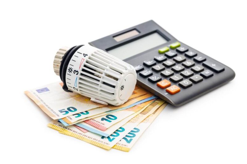 Termostat na banknotach i kalkulator symbolizują nadpłaty za centralne ogrzewanie.