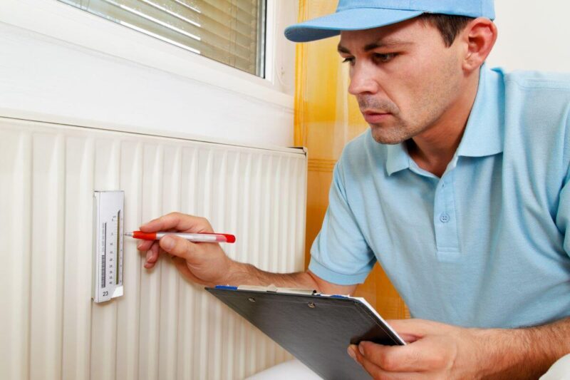 Mężczyzna sprawdza licznik ciepła we wspólnocie mieszkaniowej.