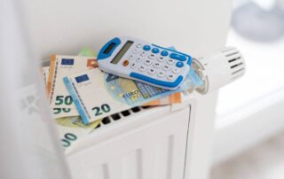 Na kaloryferze leżą euro i kalkulator, symbolizując dopłatę za ciepło.